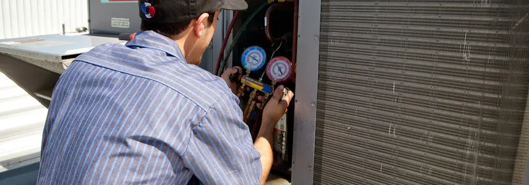 HVAC technician servicing a condenser unit in Parker